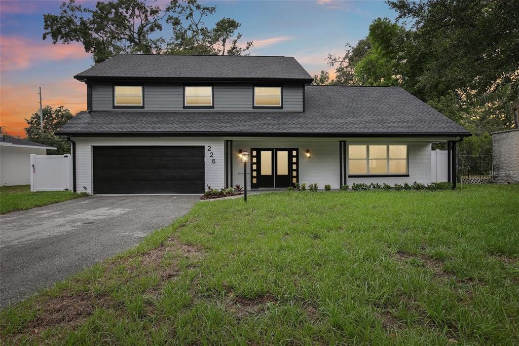 A two-story house with a white brick exterior, dark gray siding, and a black garage — 226 WILLOWICK AVENUE, TEMPLE TERRACE, FL