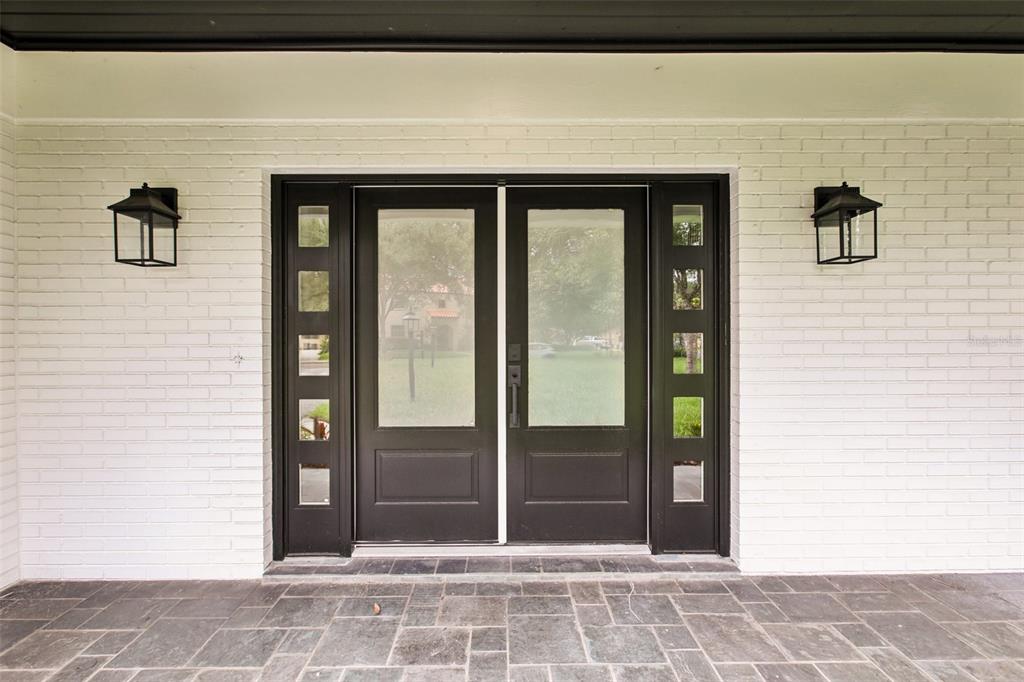 A white brick exterior wall features a modern black double door with glass panels — 226 WILLOWICK AVENUE, TEMPLE TERRACE, FL