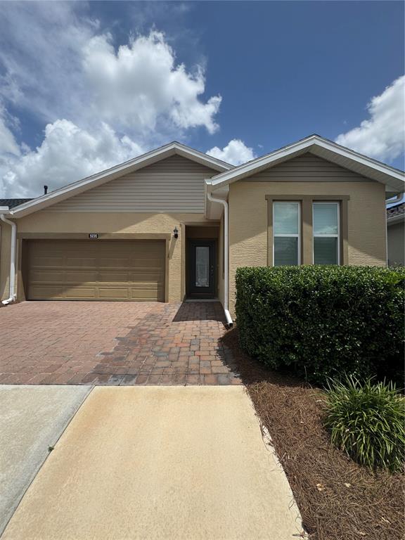 A single-story house features a tan stucco exterior, a brick paver driveway, and a garage — 5235 NW 33RD PLACE, OCALA, FL