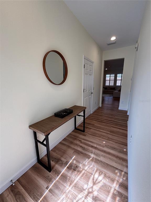 A hallway features wood-look flooring, a wooden console table, and a round wall mirror — 5235 NW 33RD PLACE, OCALA, FL