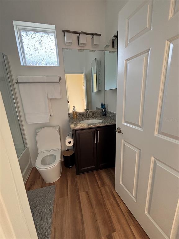A bathroom features a toilet, a dark wood vanity with a sink, and wood-look flooring — 5235 NW 33RD PLACE, OCALA, FL
