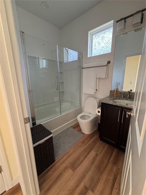 A bathroom features a glass-enclosed tub, a toilet, a dark vanity, and wood-look flooring — 5235 NW 33RD PLACE, OCALA, FL