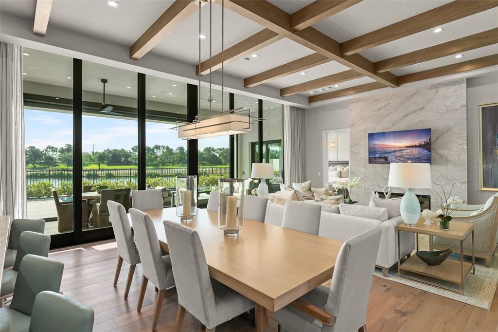A dining area with a wooden table, coffered ceiling, and large windows overlooking a lake — 4018 GRANDE BRICK LOOP, ORLANDO, FL