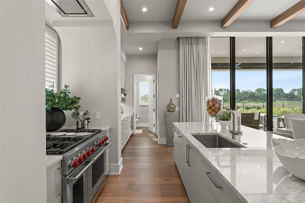 A modern kitchen features a large marble island, stainless steel range, and wood flooring — 4018 GRANDE BRICK LOOP, ORLANDO, FL