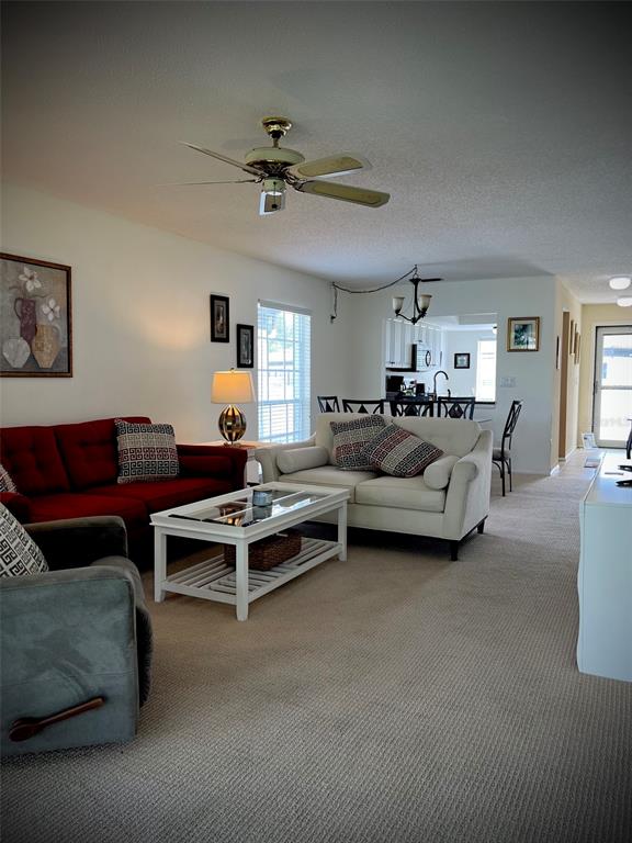 A living room with a red sofa, white loveseat, and a coffee table on carpet — 5242 WEDGEWOOD LANE UNIT 62, SARASOTA, FL
