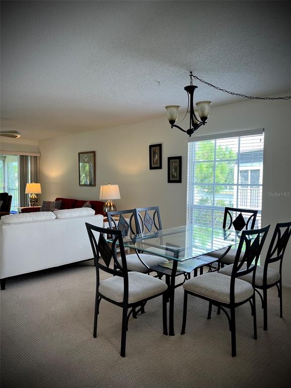 A dining area with a glass table and chairs sits next to a living room — 5242 WEDGEWOOD LANE UNIT 62, SARASOTA, FL