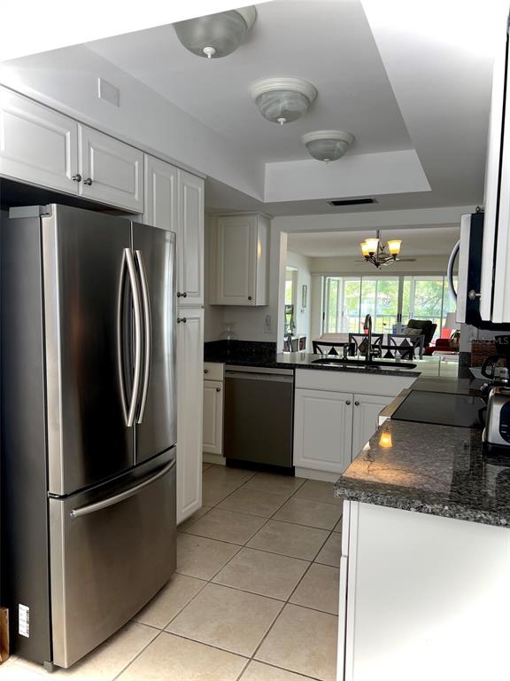 A kitchen with white cabinets, stainless steel appliances, and dark granite countertops — 5242 WEDGEWOOD LANE UNIT 62, SARASOTA, FL