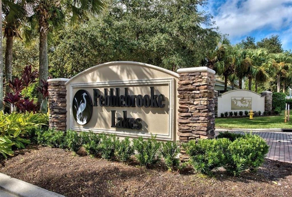 A stone and stucco monument sign marks the entrance to the Pebblebrooke Lakes community — 8390 BIG ACORN CIRCLE UNIT 1103, NAPLES, FL