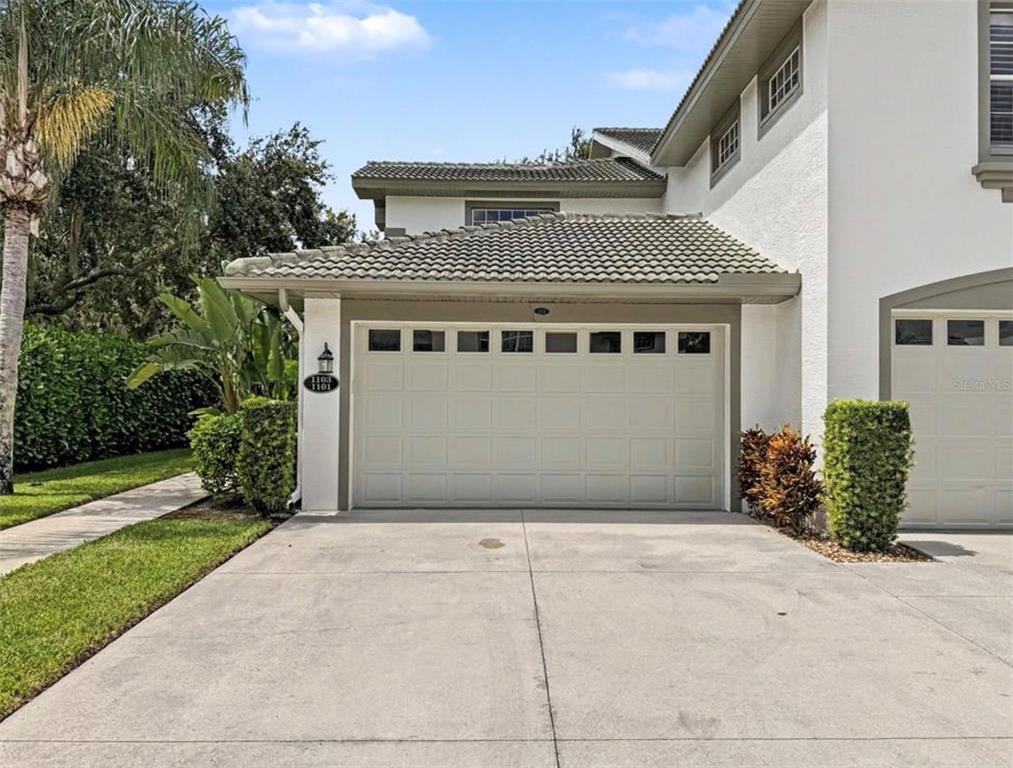 A two-car garage with a tiled roof and a concrete driveway in front of a house — 8390 BIG ACORN CIRCLE UNIT 1103, NAPLES, FL