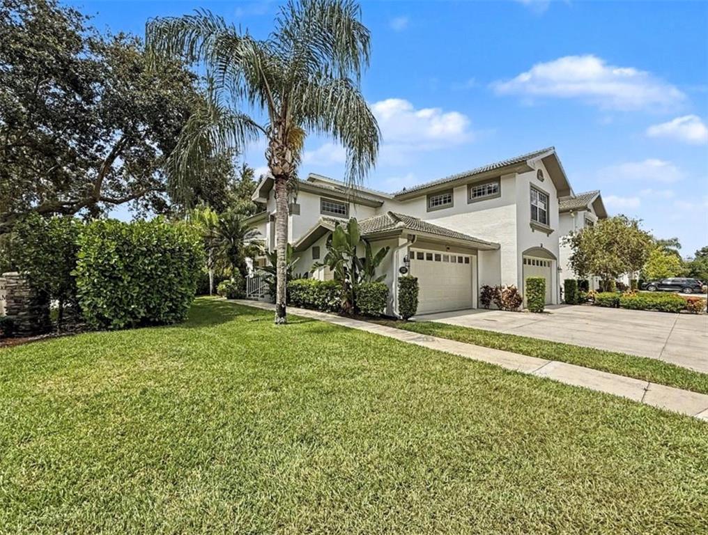A two-story house with a beige stucco exterior, a tile roof, and a two-car garage — 8390 BIG ACORN CIRCLE UNIT 1103, NAPLES, FL