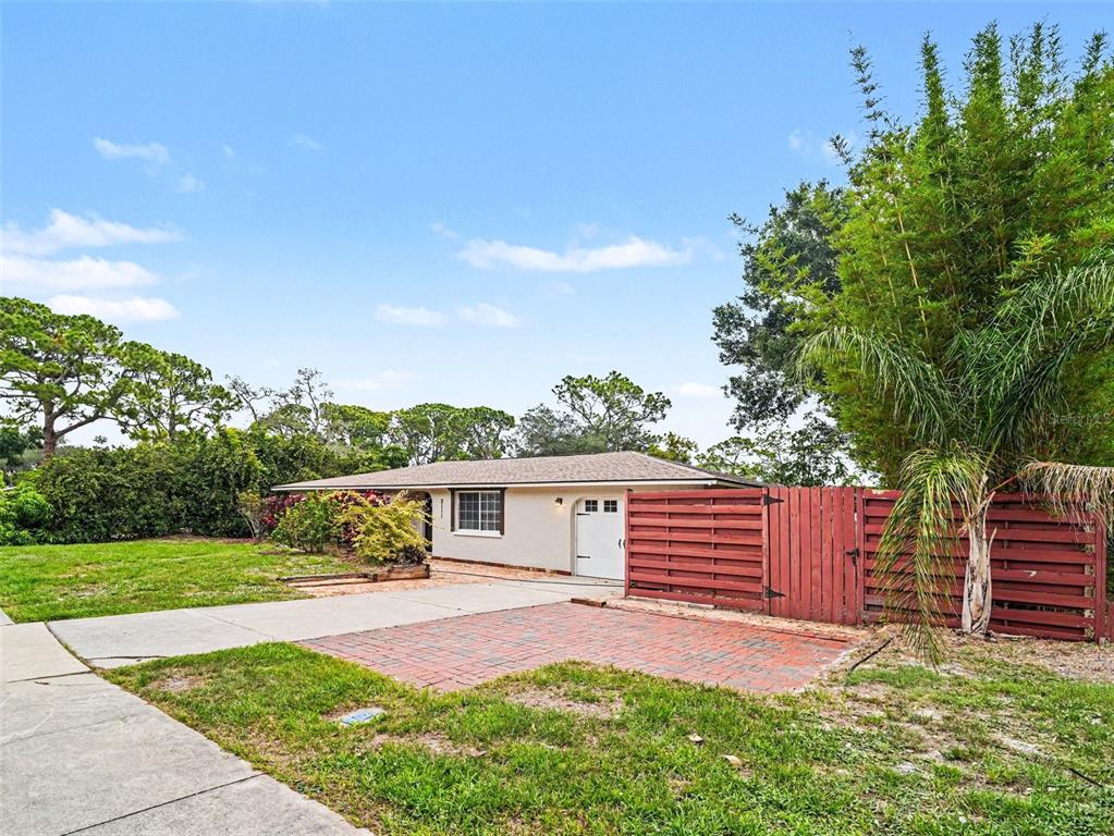 A single-story house with a white exterior, a garage, and a red wooden privacy fence — 2111 FAIRFIELD AVENUE, SARASOTA, FL