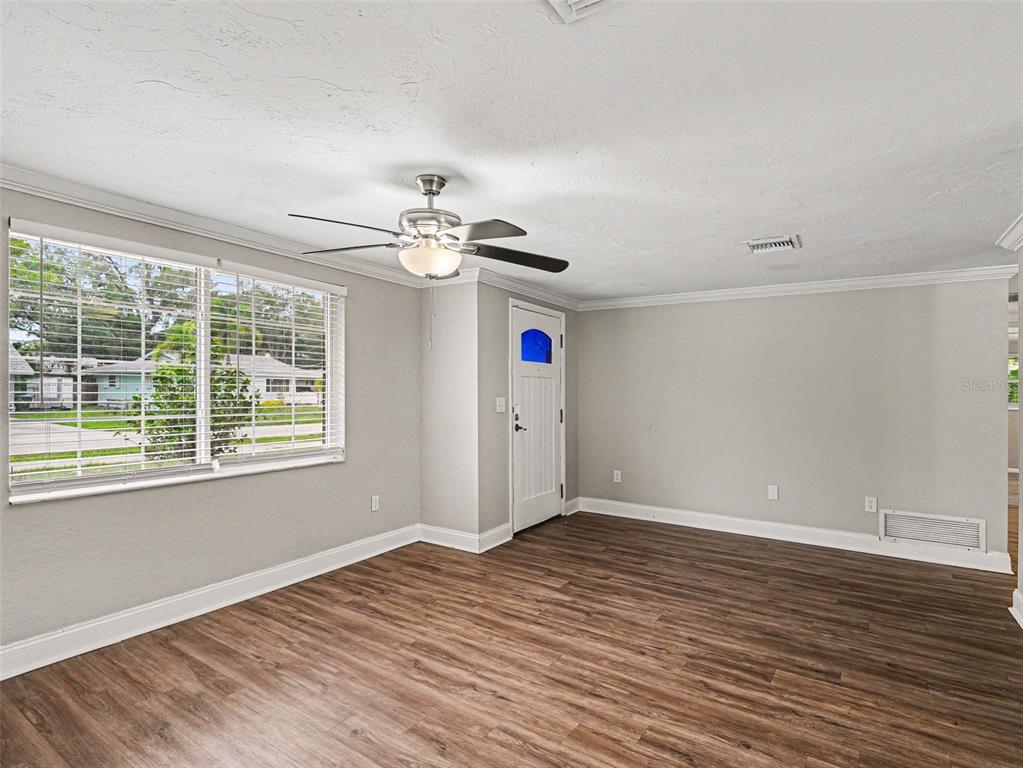 An empty room with wood-look flooring, a ceiling fan, and a white front door — 2111 FAIRFIELD AVENUE, SARASOTA, FL