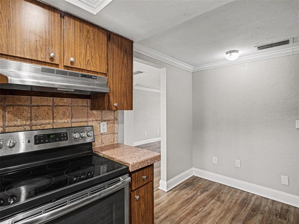 A kitchen features wood cabinets, a stainless steel stove, and a dining area with flooring — 2111 FAIRFIELD AVENUE, SARASOTA, FL