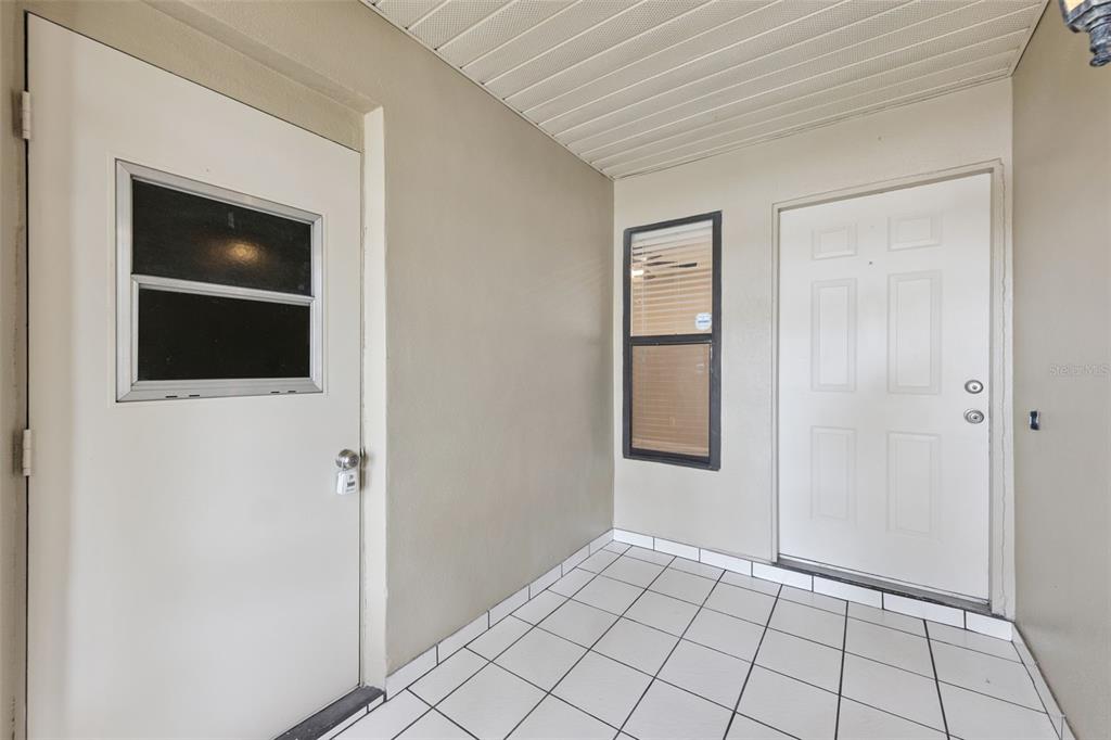 A tiled entryway features two white doors and a window on a beige wall — 1008 OLLIFF WAY, OVIEDO, FL
