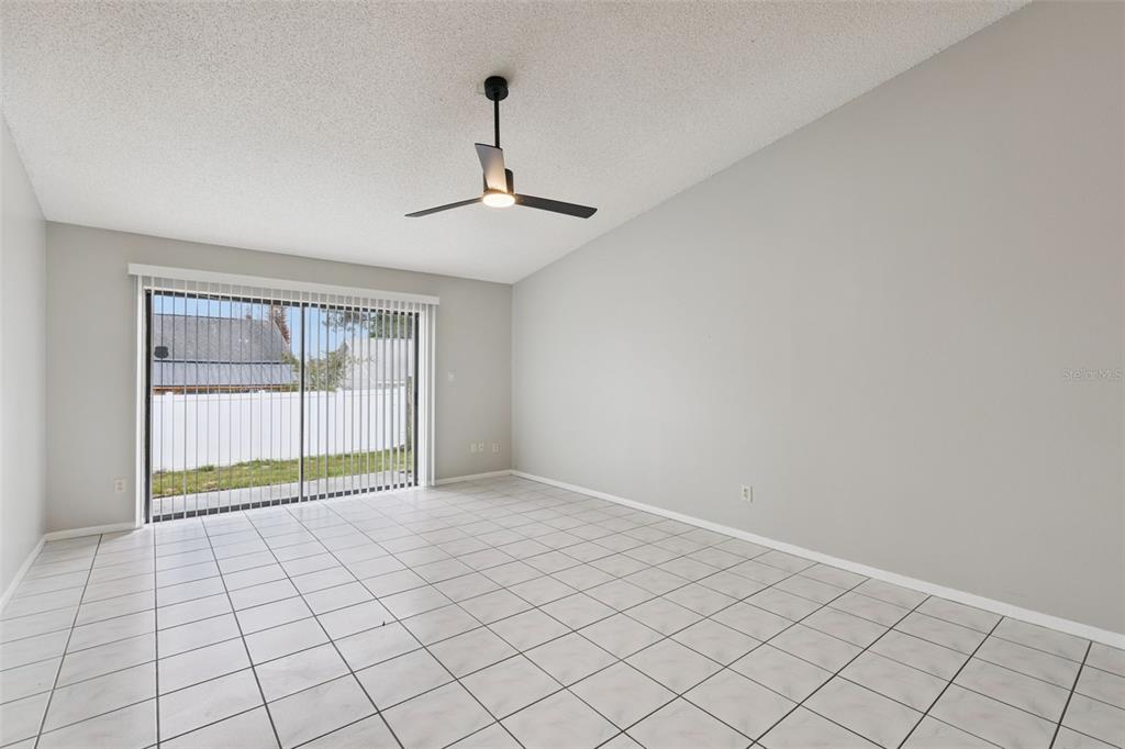An empty room features white tile flooring, light gray walls, and a sliding glass door — 1008 OLLIFF WAY, OVIEDO, FL