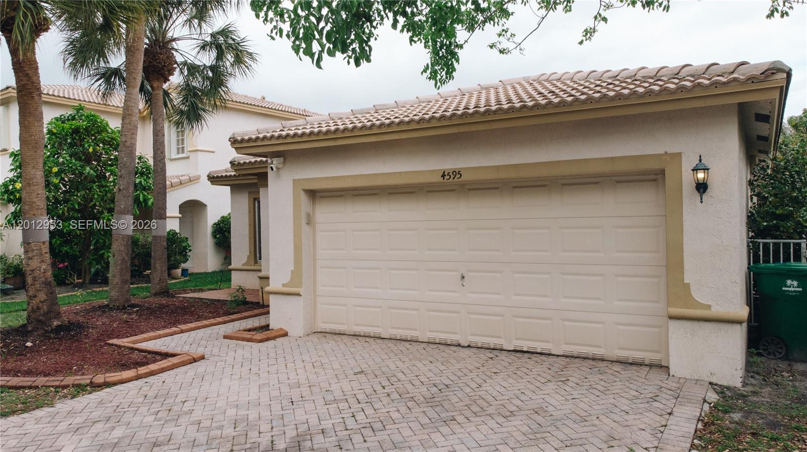 A beige two-car garage with a tiled roof and a brick paver driveway — 4595 SW 125th Ln, Miramar FL 33027, MIRAMAR, FL
