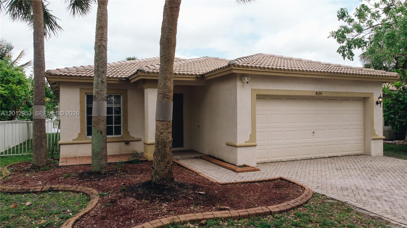 A single-story house with a beige stucco exterior, tile roof, and a paved driveway — 4595 SW 125th Ln, Miramar FL 33027, MIRAMAR, FL