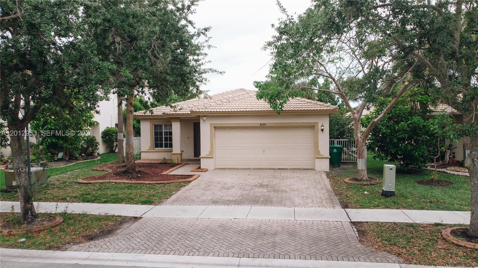 A single-story house with a beige stucco exterior, a tiled roof, and a paved driveway — 4595 SW 125th Ln, Miramar FL 33027, MIRAMAR, FL
