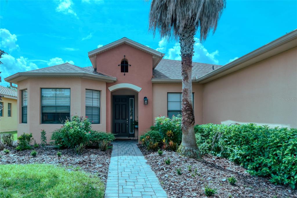 A single-story house with a peach-colored stucco exterior, a stone walkway, and a palm tree — 280 INDIAN WELLS AVENUE, KISSIMMEE, FL
