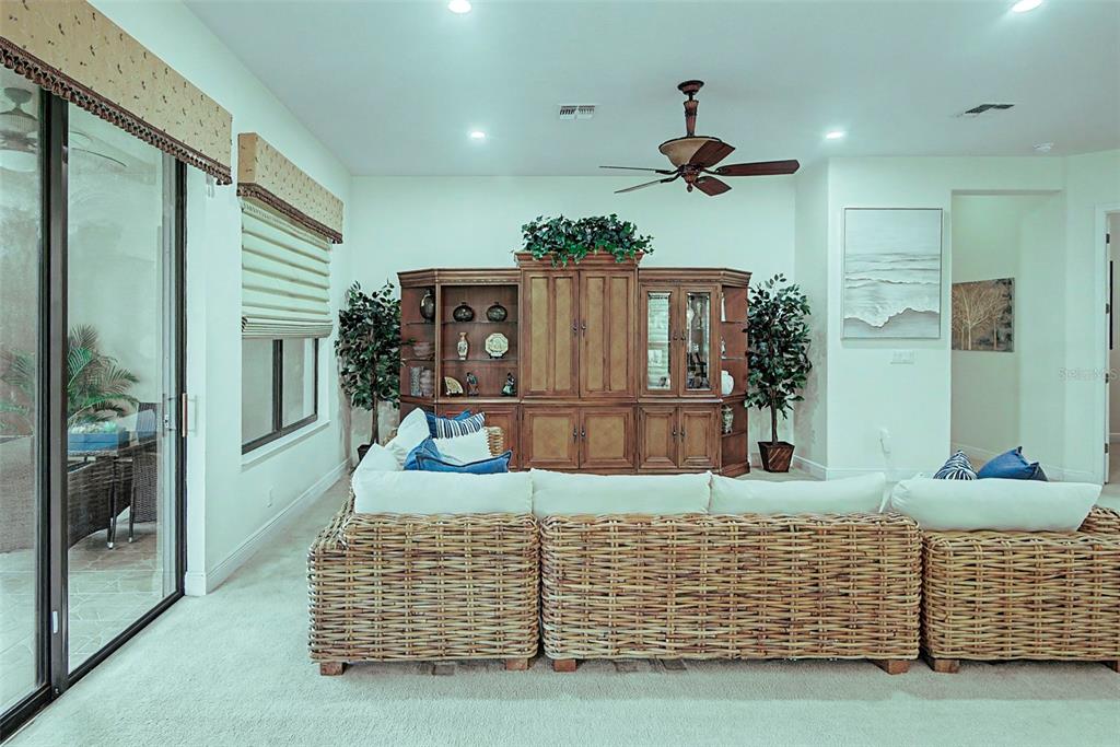 A living room features a large wicker sectional sofa, a wooden entertainment center, and sliding doors — 280 INDIAN WELLS AVENUE, KISSIMMEE, FL