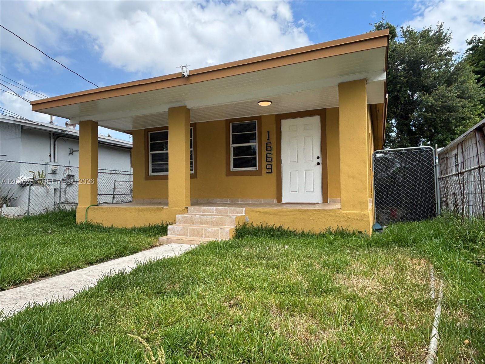 A yellow single-story house features a covered front porch with steps and a white door — 1669 NW 70th St, Miami FL 33147, MIAMI, FL
