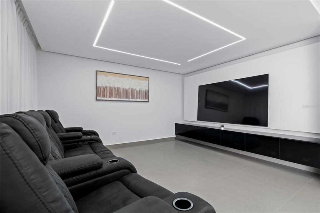 A modern home theater features dark reclining seats, a large wall-mounted television, and recessed lighting — 96 CALLE AMAZONAS, BAYAMON, PR