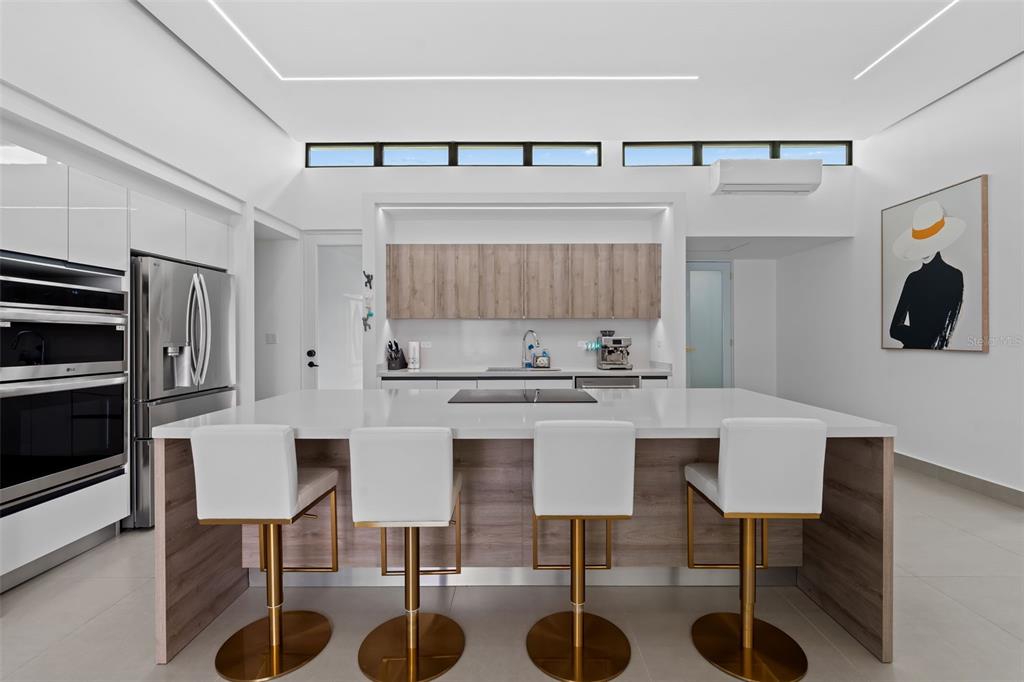 A modern kitchen features a large island with four bar stools and white cabinetry — 96 CALLE AMAZONAS, BAYAMON, PR