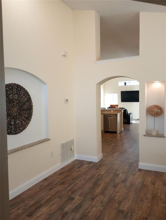 An interior view showing arched wall niches, wood-look flooring, and a view into the kitchen — 7947 GOLDEN POND CIRCLE, KISSIMMEE, FL