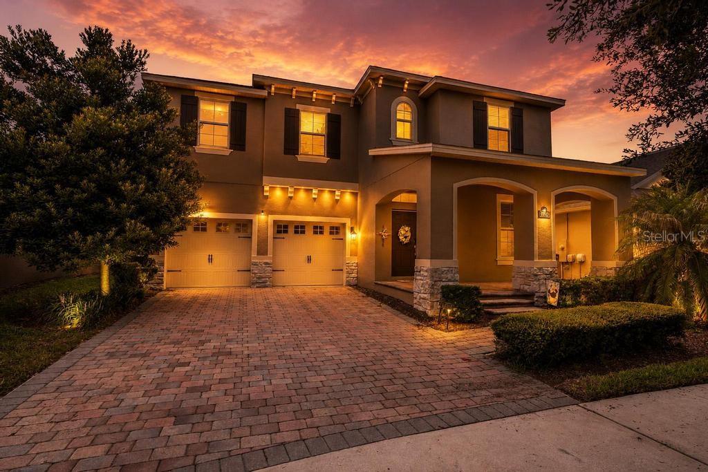 A two-story house with a paved driveway, two-car garage, and stone accents at dusk — 15512 FOUNTAIN COVE COURT, WINTER GARDEN, FL
