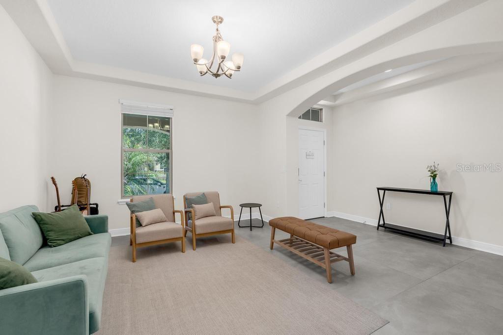 A living room features a light green sofa, two armchairs, a bench, and tile flooring — 15512 FOUNTAIN COVE COURT, WINTER GARDEN, FL