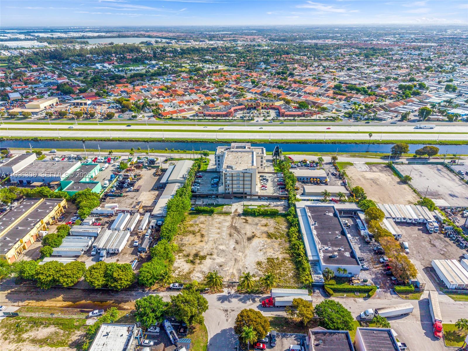 An aerial view shows a multi-story building surrounded by parking lots, vacant land, and highways — 10633 NW 123rd St Rd, Medley FL 33178, MEDLEY, FL