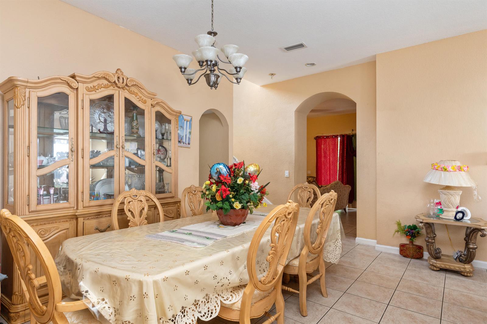 A dining room features a wooden hutch, a table with six chairs, and tile flooring — 1017 Grove Park Circle, Boynton Beach FL 33436, BOYNTON BEACH, FL