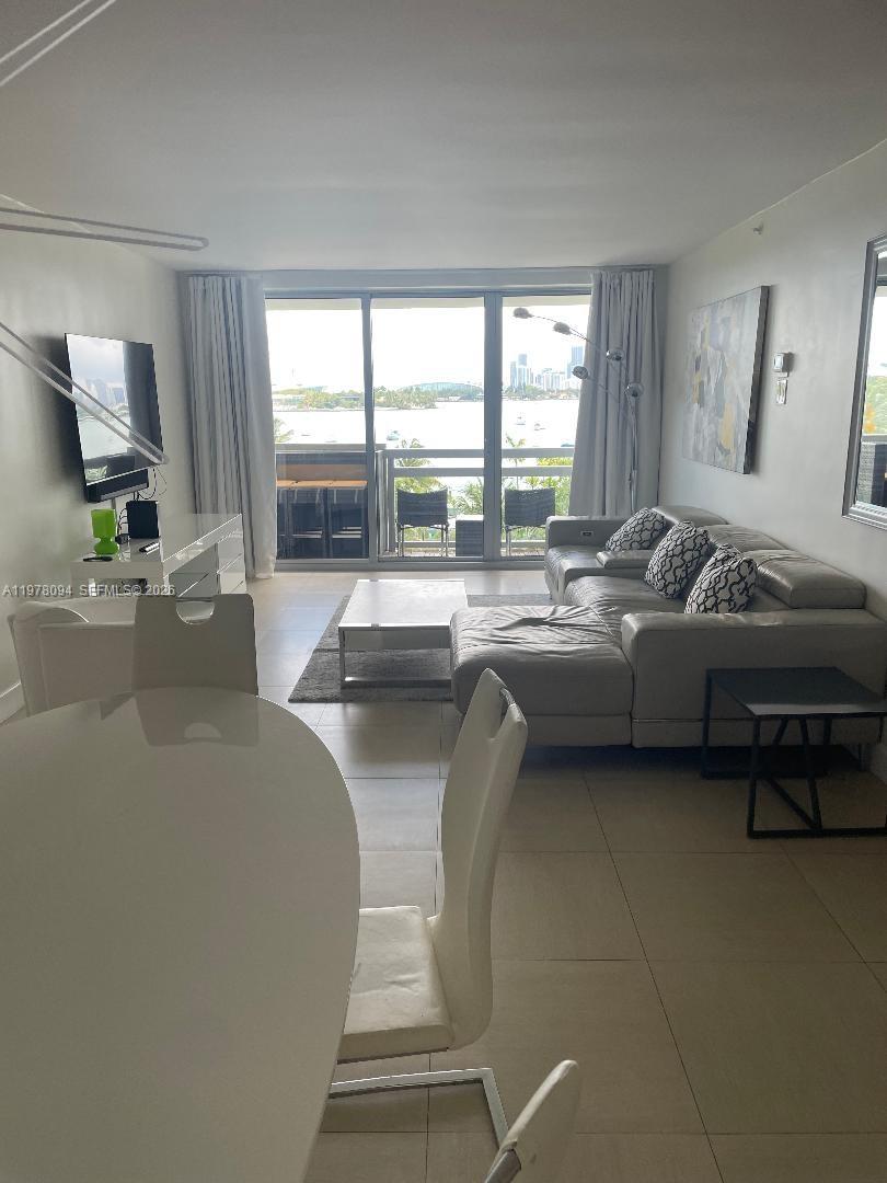 A living and dining area features tile floors, a sectional sofa, and a balcony view — 1500 Bay Rd # 524S, Miami Beach FL 33139, MIAMI BEACH, FL