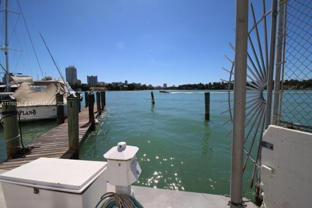 A wooden dock extends into a bay with a boat moored alongside a city skyline — 900 Bay Dr, Miami Beach FL 33141, MIAMI BEACH, FL