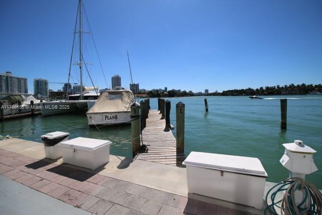 A wooden dock extends into a bay with several boats moored nearby under a clear sky — 900 Bay Dr, Miami Beach FL 33141, MIAMI BEACH, FL