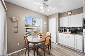 A dining area with a round wooden table, chairs, ceiling fan, and white kitchen cabinets — 1001 PLANTATION DRIVE UNIT B2, KISSIMMEE, FL