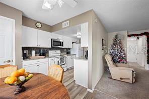 A kitchen with white cabinets and a dining area with a wooden table — 1001 PLANTATION DRIVE UNIT B2, KISSIMMEE, FL
