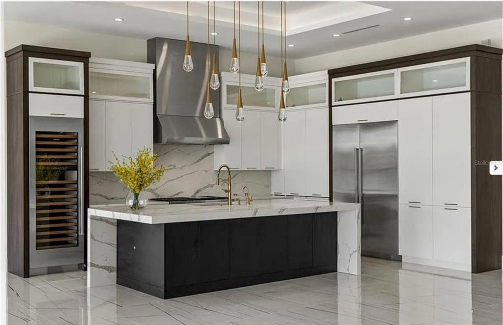 A modern kitchen features a marble waterfall island, dark cabinetry, and stainless steel appliances — 6606 SAWYER SHORES LANE, WINDERMERE, FL
