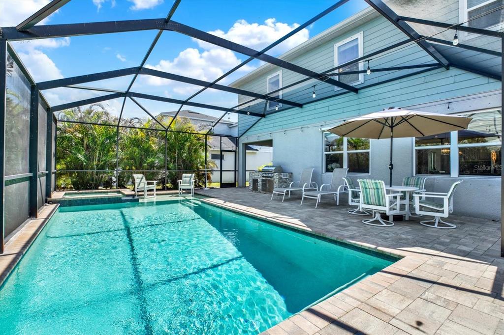 A screened-in patio features a swimming pool, a hot tub, and outdoor dining furniture — 11702 LAKE LUCAYA DRIVE, RIVERVIEW, FL