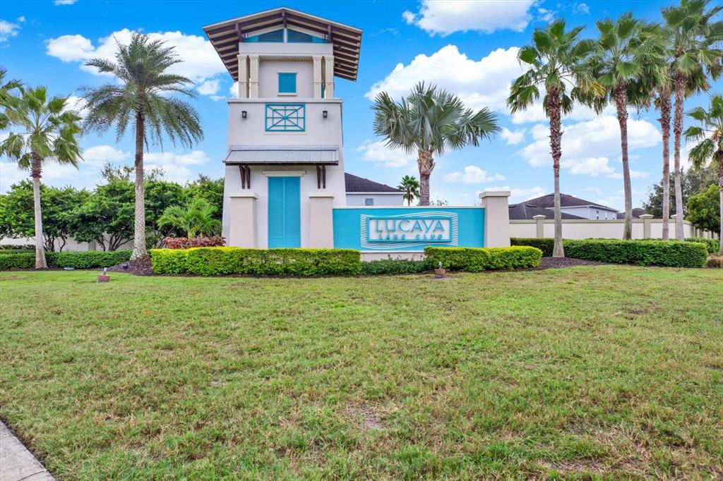 A sign for Lucaya Lake Club stands in front of a tower and palm trees — 11702 LAKE LUCAYA DRIVE, RIVERVIEW, FL