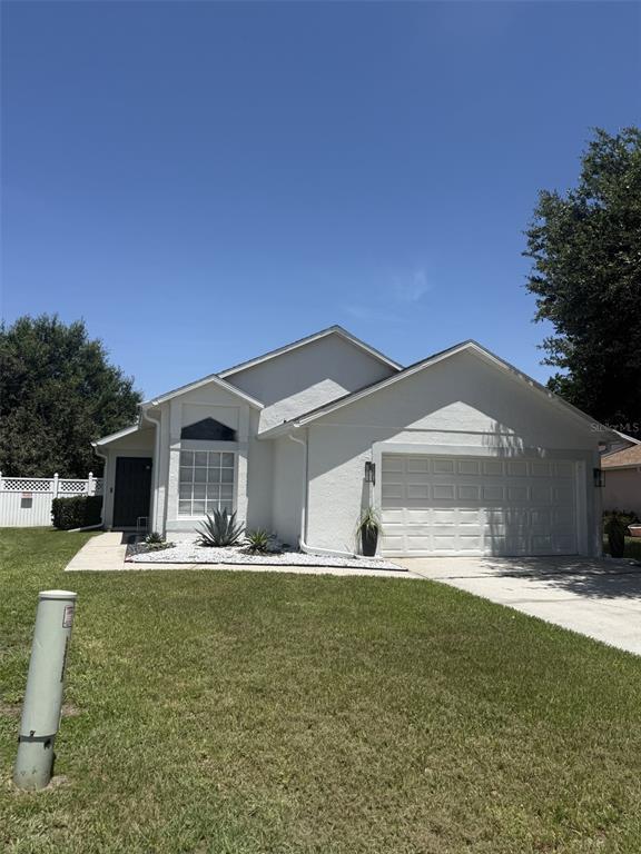 A single-story white house with a two-car garage and a small front garden — 2916 CANOE CIRCLE, ST CLOUD, FL