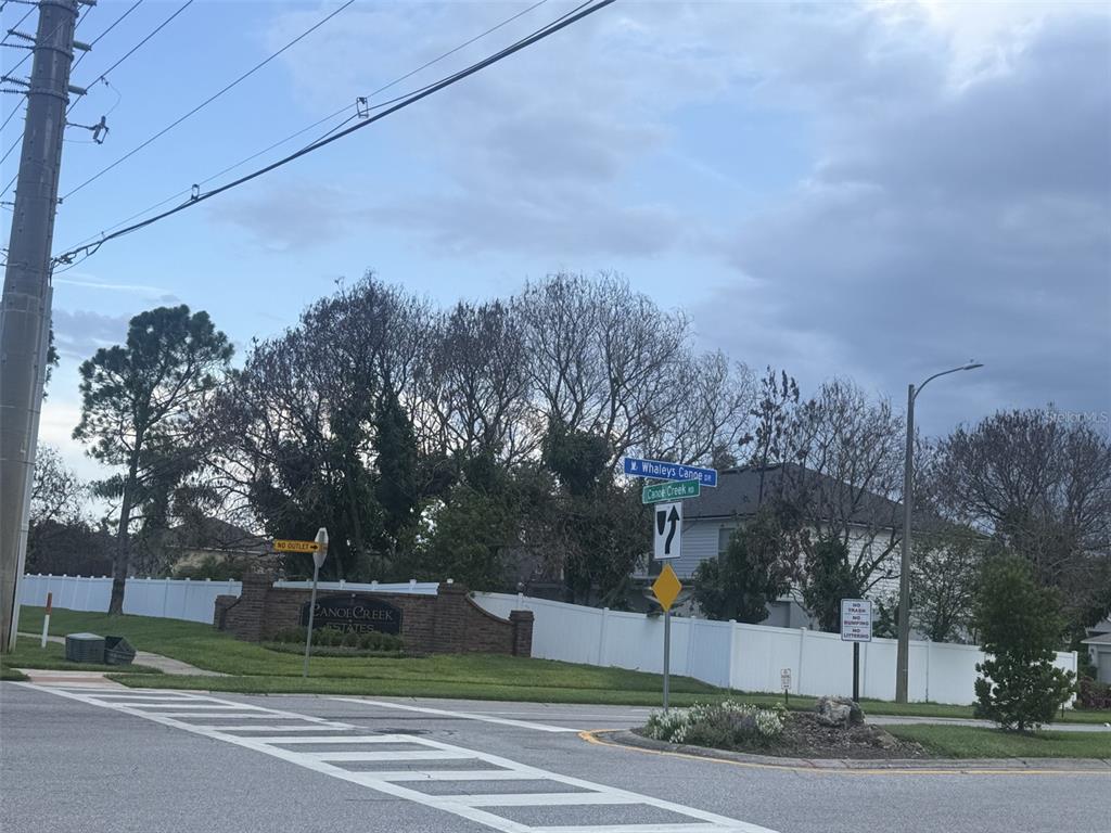 A street corner view shows the entrance sign for Canoe Creek Estates with road signs — 2916 CANOE CIRCLE, ST CLOUD, FL