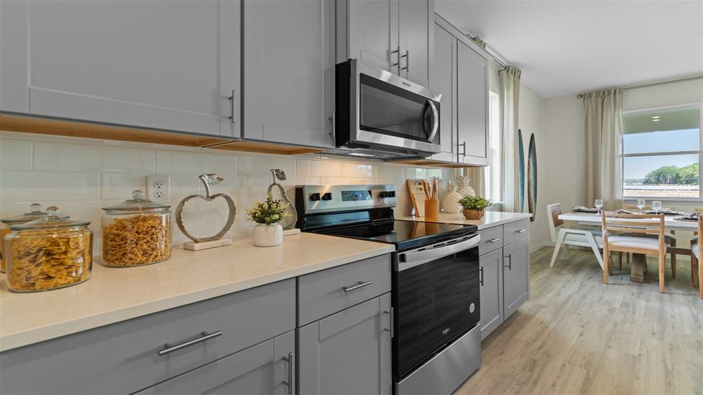 A kitchen with gray cabinets, stainless steel appliances, and quartz countertops overlooks a dining area — 314 SKATEMASTER STREET, ORMOND BEACH, FL