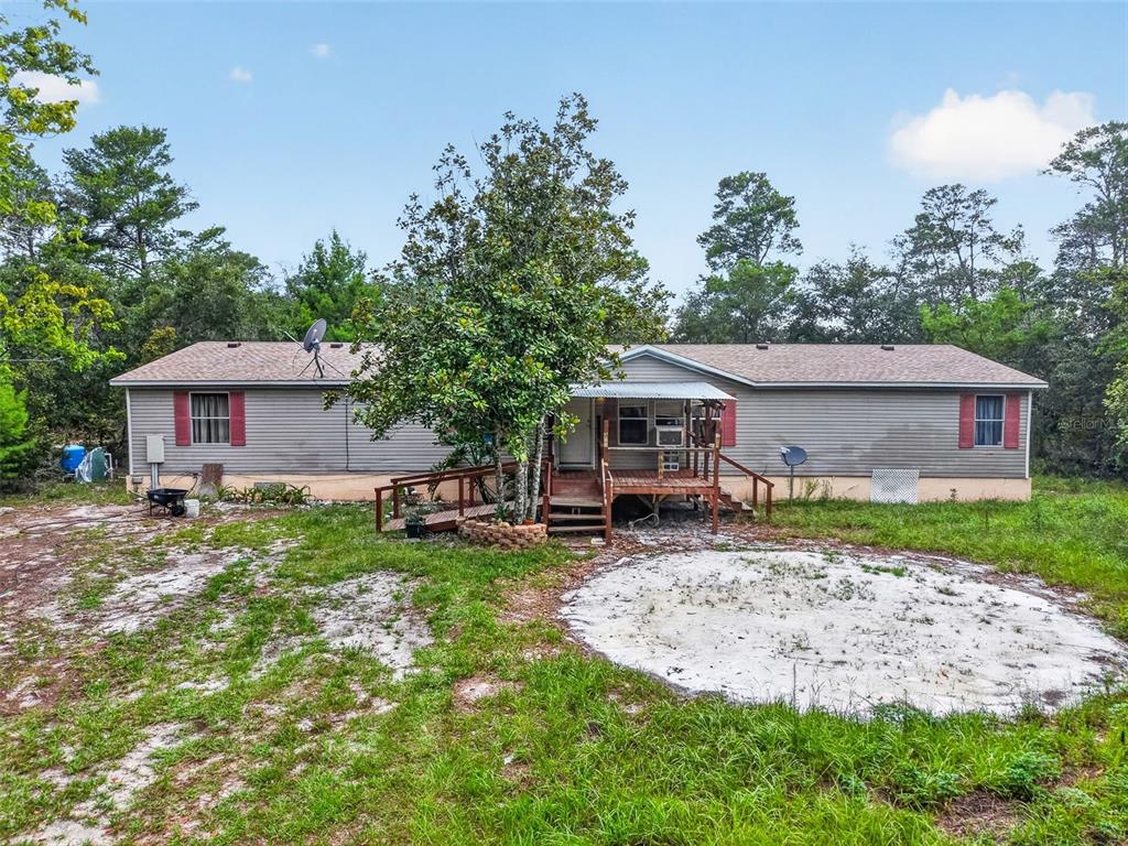 A single-story manufactured home with grey siding, a wooden front deck, and a wheelchair ramp — 20241 SALTSDALE ROAD, UMATILLA, FL