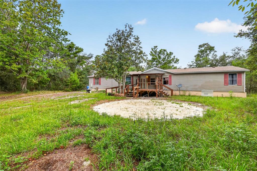 A single-story manufactured home with light siding and red shutters sits on a grassy lot — 20241 SALTSDALE ROAD, UMATILLA, FL