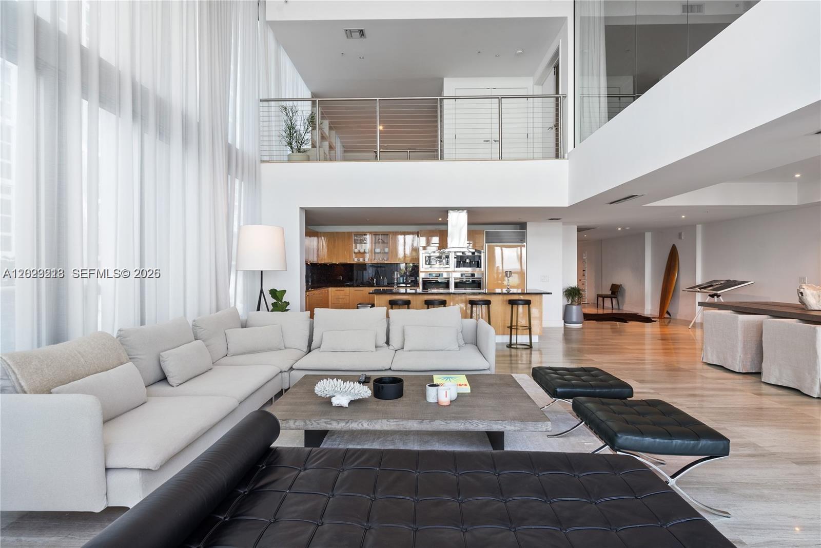 A modern, open-concept living area features a large sectional sofa, kitchen island, and mezzanine level — 6899 Collins Ave # 202, Miami Beach FL 33141, MIAMI BEACH, FL