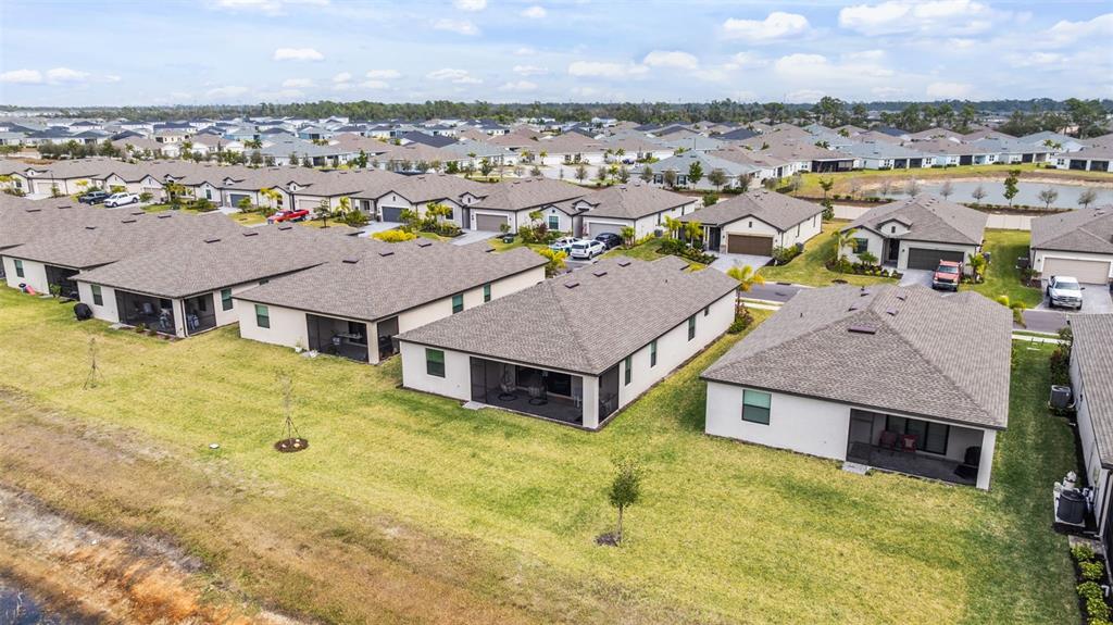 An aerial view shows a suburban street with single-family homes and a nearby canal — 1505 SADDLEWOOD CIRCLE, PORT CHARLOTTE, FL