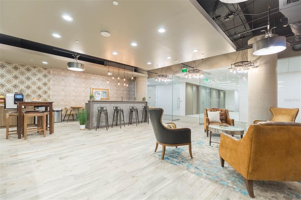 A modern office lounge features a bar area, leather armchairs, and a patterned accent wall — 400 N ASHLEY DRIVE UNIT 2653, TAMPA, FL