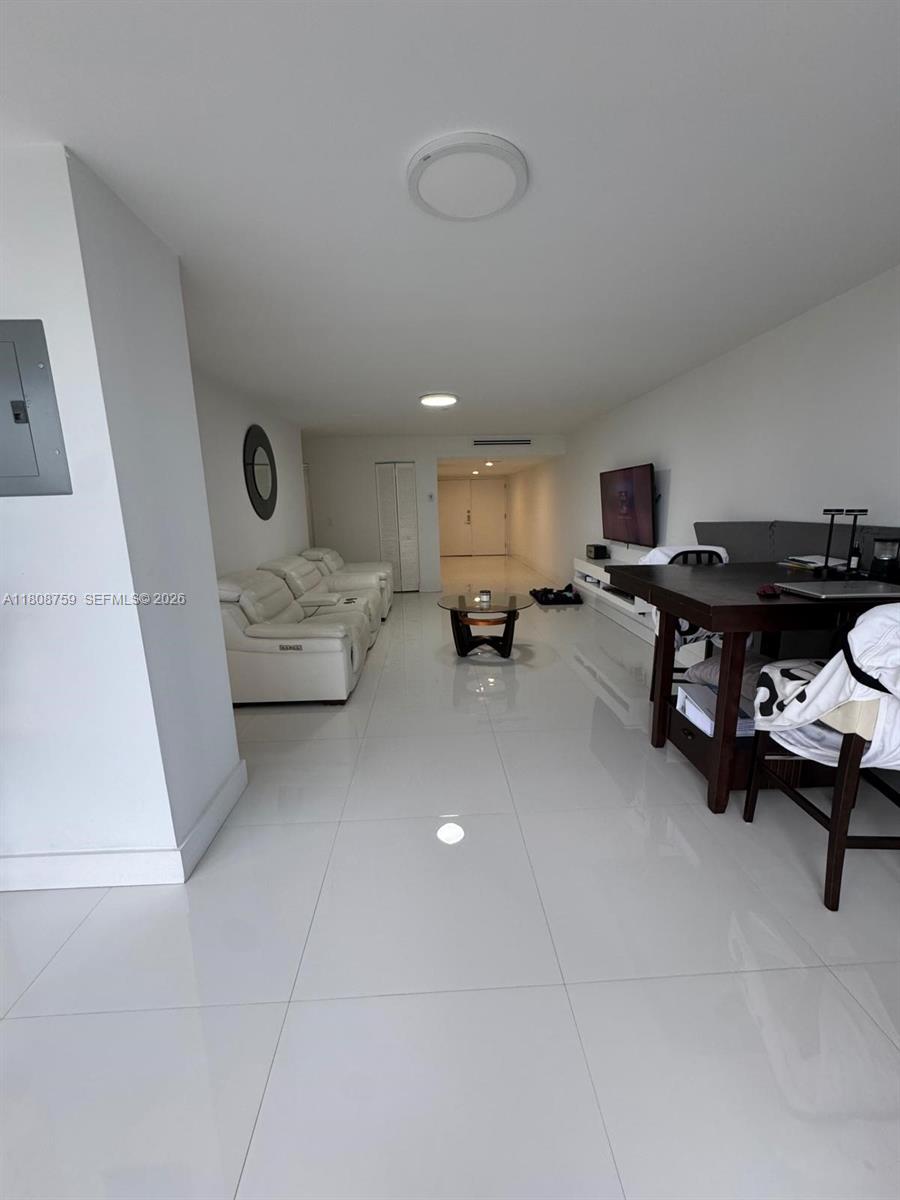 This open-concept living and dining area features white tile floors and modern white furniture — 6423 Collins Ave # 1001, Miami Beach FL 33141, MIAMI BEACH, FL