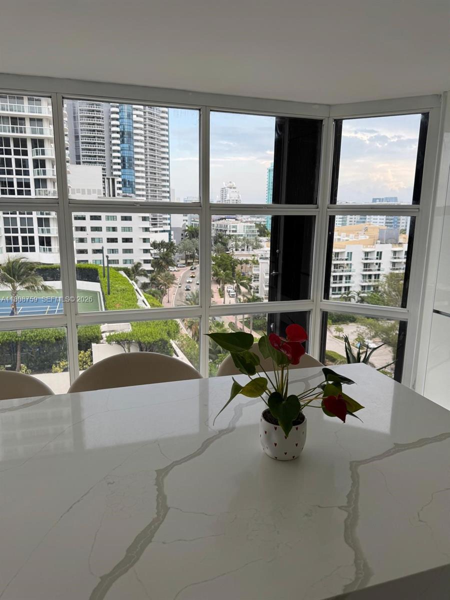 A dining area features a white marble table with a potted plant before floor-to-ceiling windows — 6423 Collins Ave # 1001, Miami Beach FL 33141, MIAMI BEACH, FL